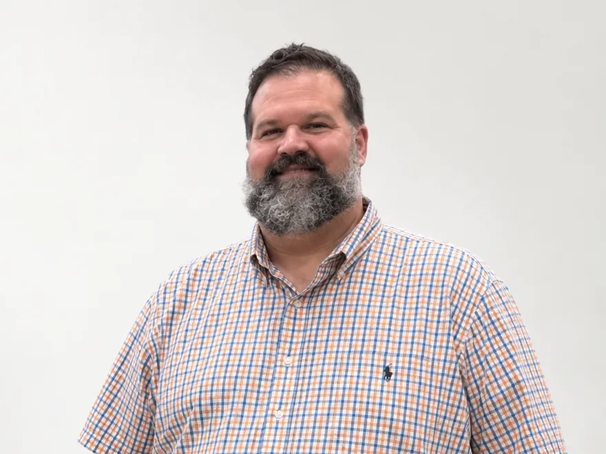 Tim, smiling, in a checked short-sleeved shirt